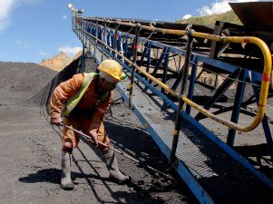 A worker sweeps up coal.