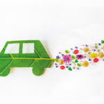 Environmentally friendly car cut out on a green leaf with flowers coming from the exhaust
